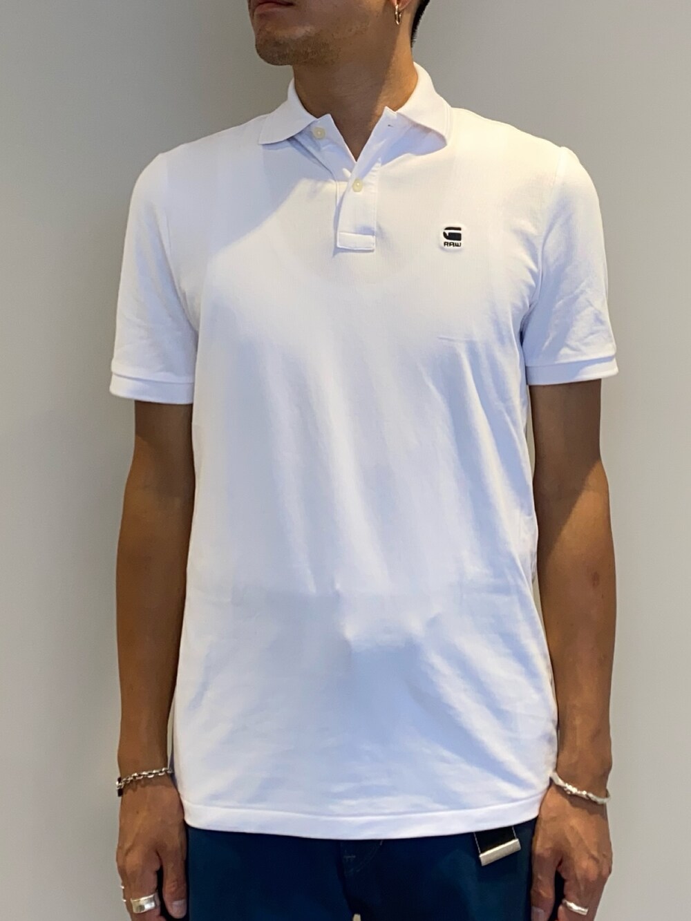 ホワイト系のポロシャツ、ブルー系のデニムパンツを着用したメンズの夏コーディネートの2枚目の写真