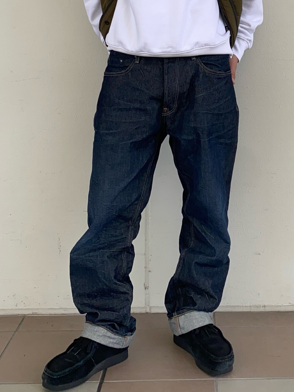 ブルー系のデニムパンツ、グリーン系のダウンベスト、ホワイト系のスウェットを着用したメンズの秋コーディネートの3枚目の写真