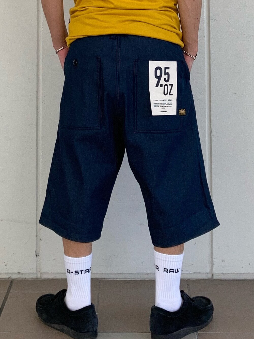 イエロー系のTシャツ/カットソー、ブルー系のデニムパンツ、ブルー系のキャップを着用したメンズの夏コーディネートの3枚目の写真