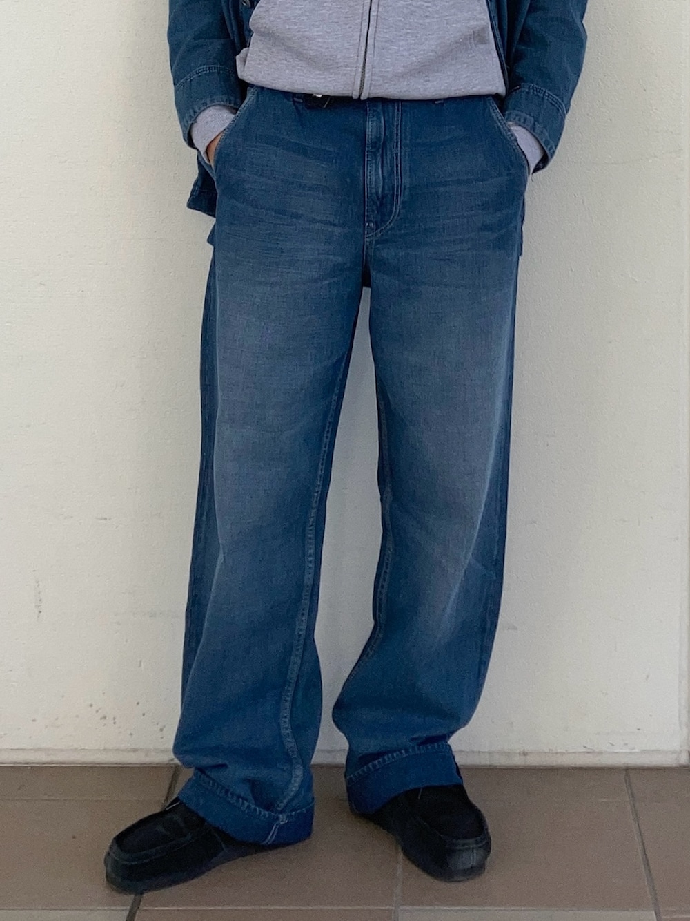 グレー系のパーカー、ブルー系のカバーオール、ブルー系のデニムパンツを着用したメンズの冬コーディネートの3枚目の写真