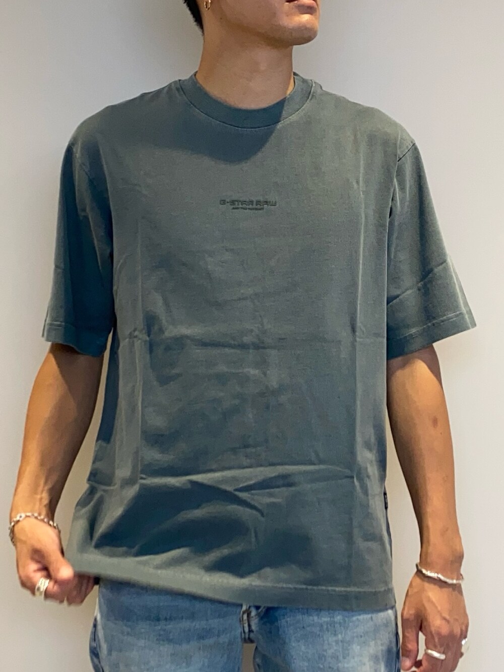 グリーン系のTシャツ/カットソー、ブルー系のデニムパンツ、その他のスニーカーを着用したメンズの夏コーディネートの2枚目の写真