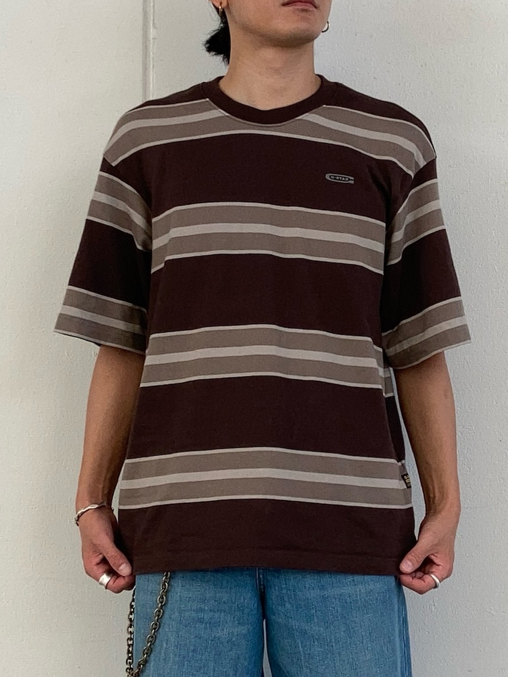 ブルー系のデニムパンツ、ブラウン系のTシャツ/カットソーを着用したメンズの夏コーディネートの2枚目の写真