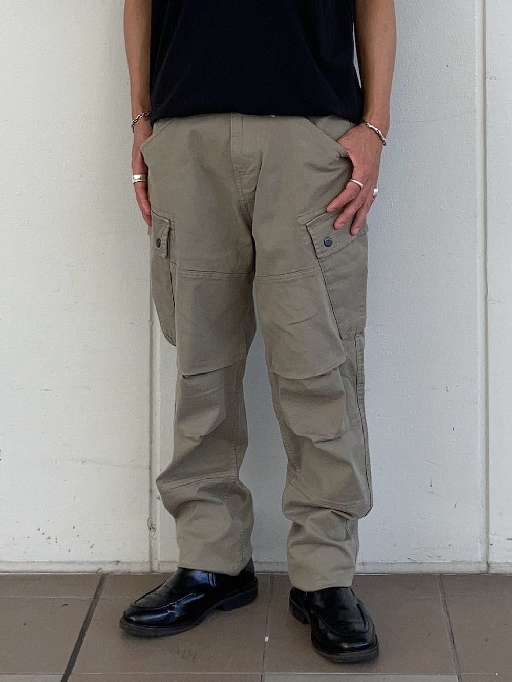 ブラック系のTシャツ/カットソー、ベージュ系のカーゴパンツ、ブラック系のブーツを着用したメンズの夏コーディネートの2枚目の写真