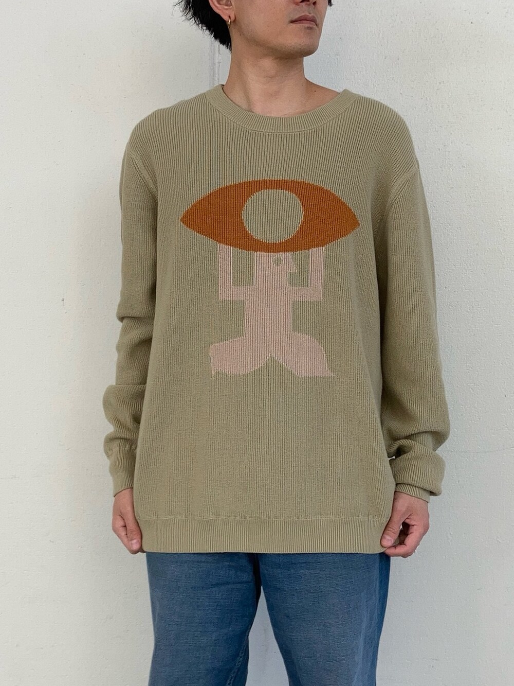 グリーン系のニット/セーター、ブルー系のデニムパンツを着用したメンズの春コーディネートの2枚目の写真