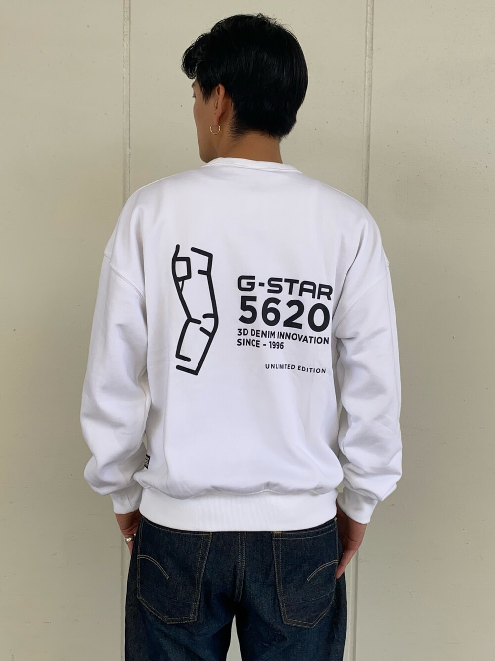 ブルー系のデニムパンツ、グリーン系のダウンベスト、ホワイト系のスウェットを着用したメンズの秋コーディネートの2枚目の写真