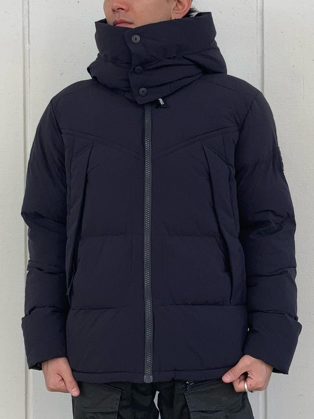 ブラック系のダウンジャケット/コート、グリーン系のカーゴパンツ、ベージュ系のニット/セーターを着用したメンズの秋コーディネートの2枚目の写真