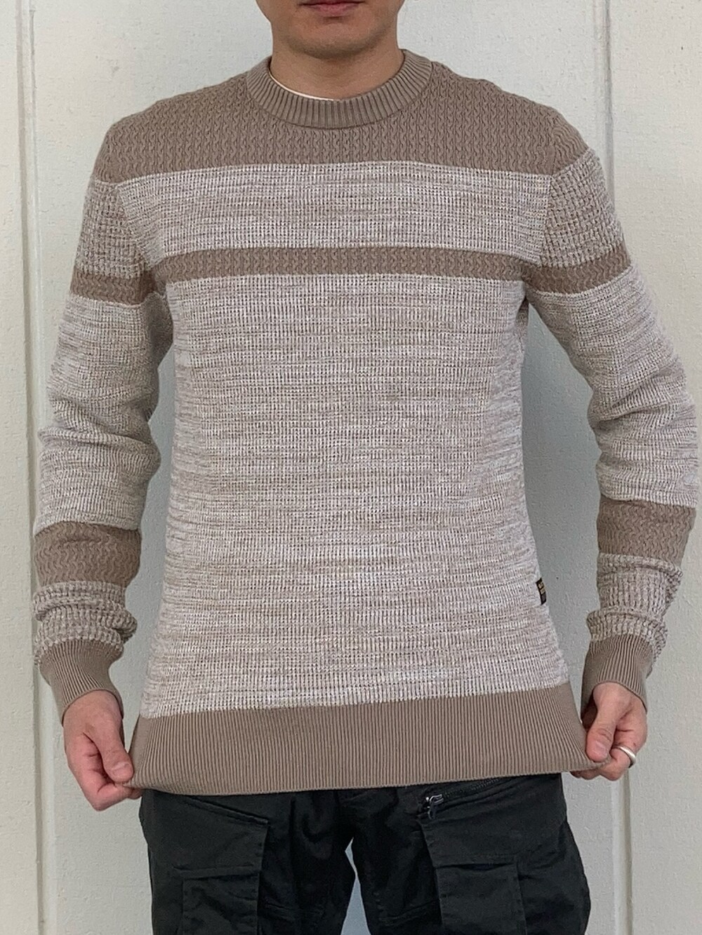 ブラック系のダウンジャケット/コート、グリーン系のカーゴパンツ、ベージュ系のニット/セーターを着用したメンズの秋コーディネートの3枚目の写真