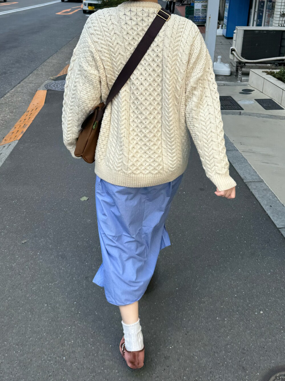 ブラウン系のショルダーバッグ、ベージュ系のカーディガン/ボレロ、ブルー系のシャツワンピースを着用したレディースの春コーディネートの2枚目の写真