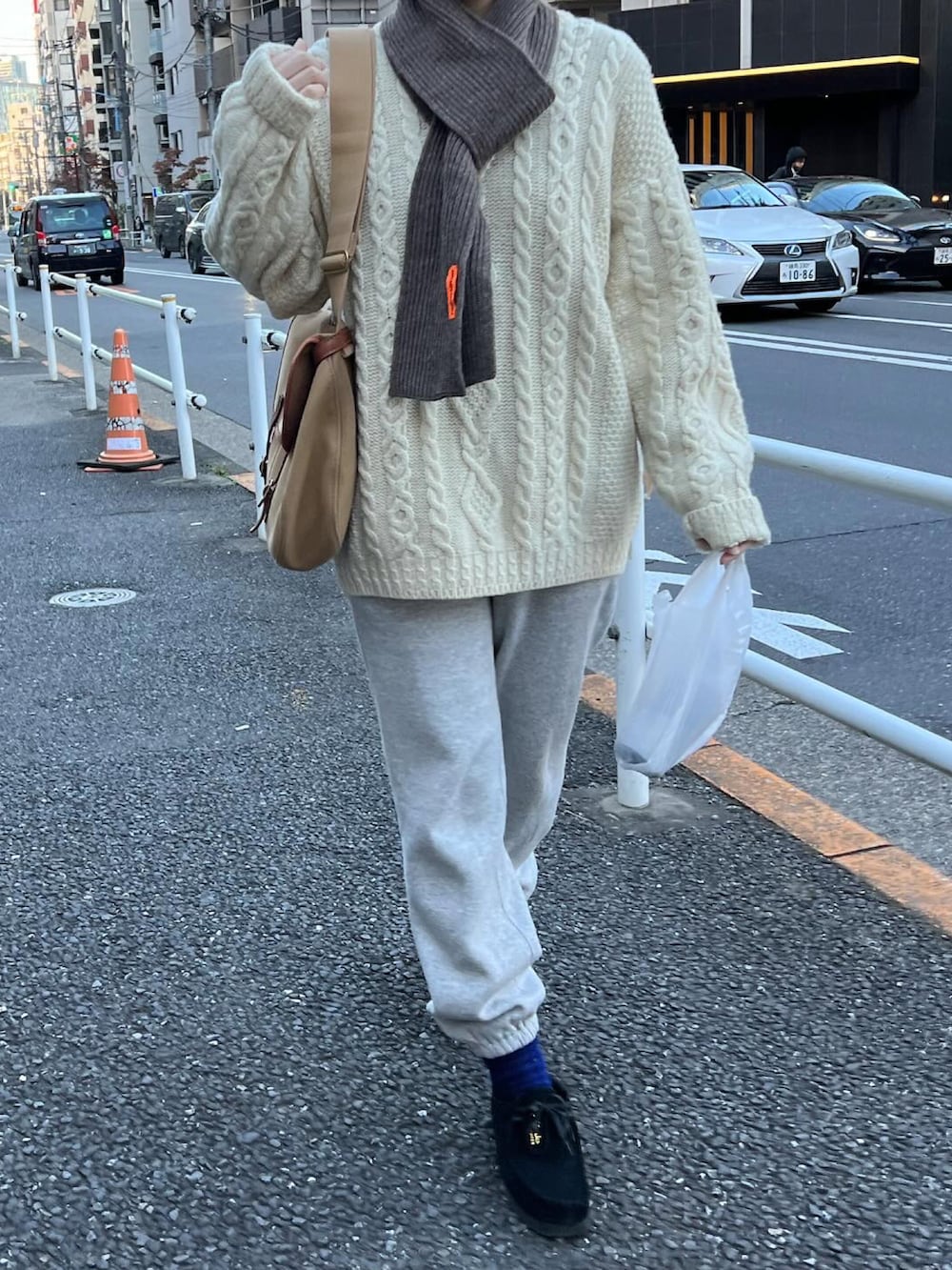 ベージュ系のショルダーバッグ、グレー系のスウェットパンツ、ブラック系のモカシン/デッキシューズを着用したレディースの冬コーディネートの2枚目の写真