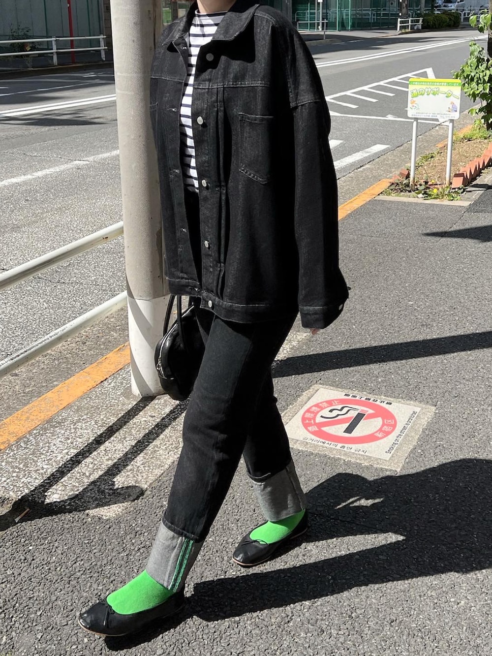 ブラック系のデニムジャケット、ブラック系のバレエシューズ、ブラック系のデニムパンツを着用したレディースの春コーディネートの2枚目の写真