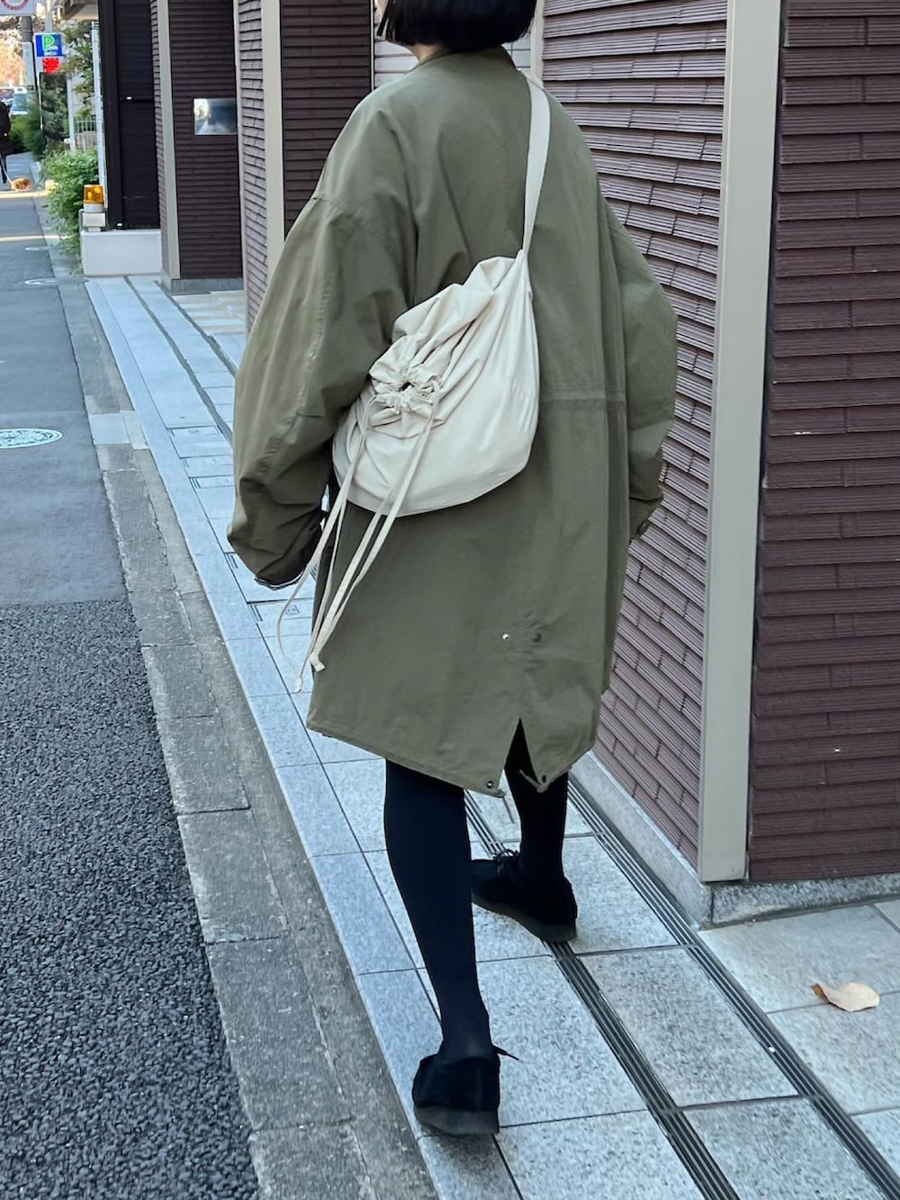 グリーン系のモッズコート、ブラック系のモカシン/デッキシューズ、ブルー系のスカートを着用したレディースの秋コーディネートの3枚目の写真