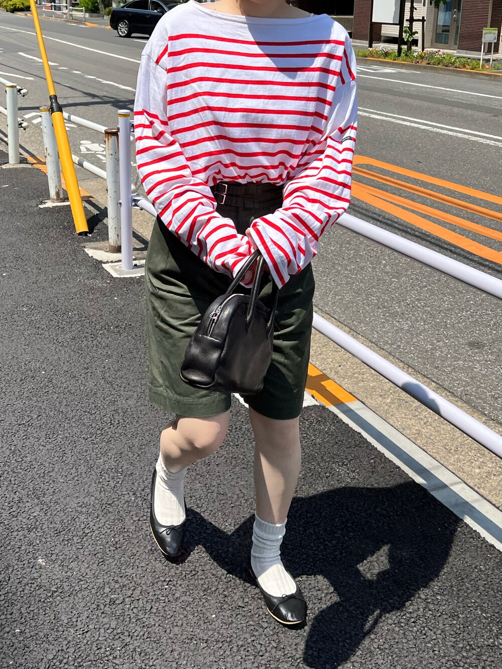 グリーン系のパンツ、ブラック系のボストンバッグ、ブラック系のバレエシューズを着用したレディースの春コーディネートの2枚目の写真