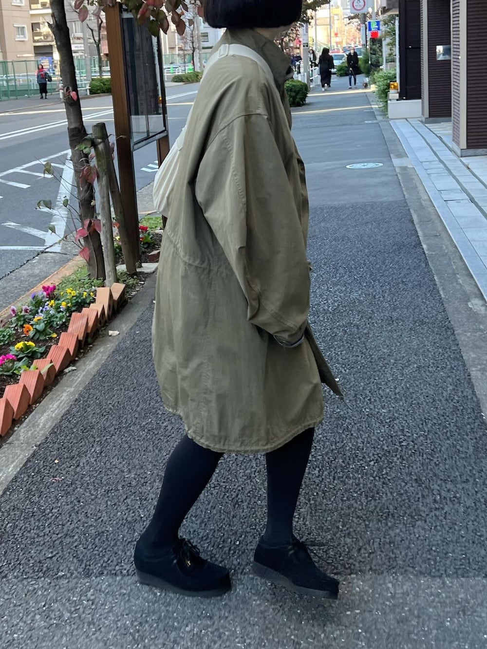 グリーン系のモッズコート、ブラック系のモカシン/デッキシューズ、ブルー系のスカートを着用したレディースの秋コーディネートの2枚目の写真