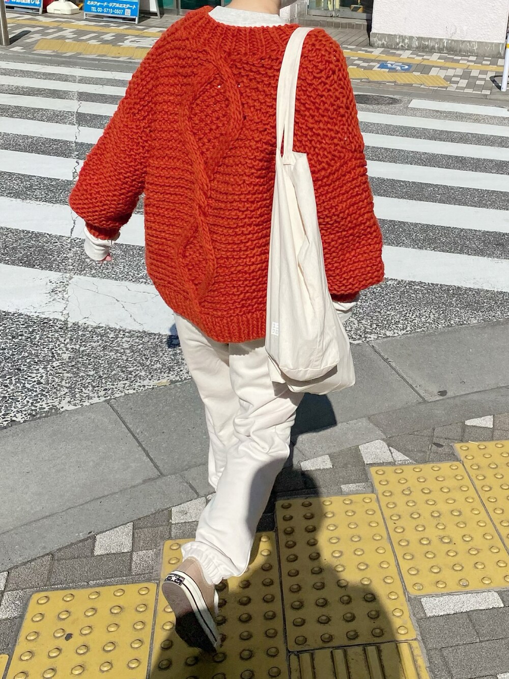 オレンジ系のカーディガン/ボレロ、グレー系のスウェット、ホワイト系のスウェットパンツを着用したレディースの秋コーディネートの2枚目の写真