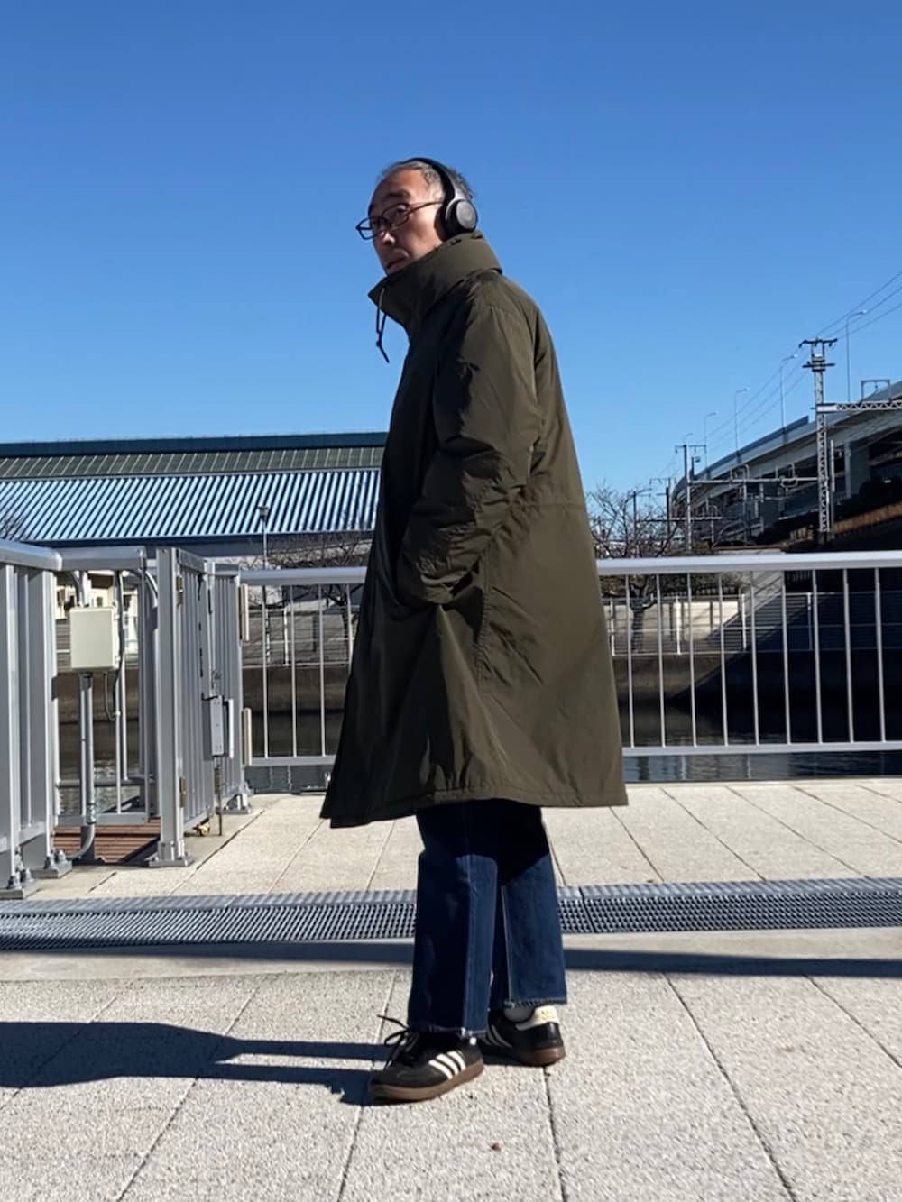 ベージュ系のダウンジャケット/コート、ブルー系のデニムパンツ、ブラック系のスニーカーを着用したメンズの冬コーディネートの2枚目の写真