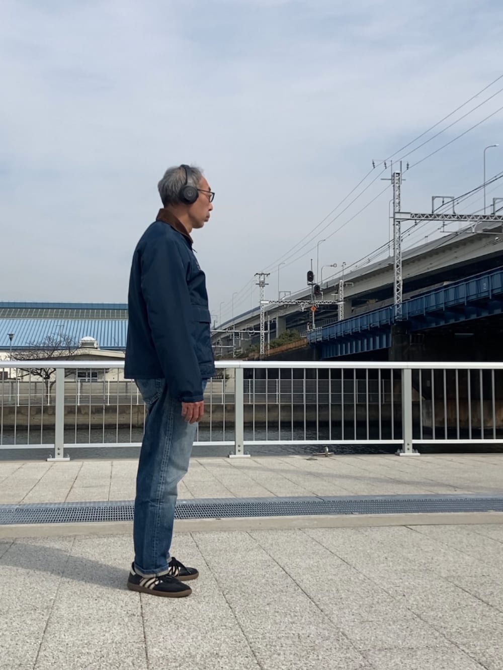 ブルー系のナイロンジャケット、ブルー系のデニムパンツ、ブラック系のスニーカーを着用したメンズの冬コーディネートの3枚目の写真