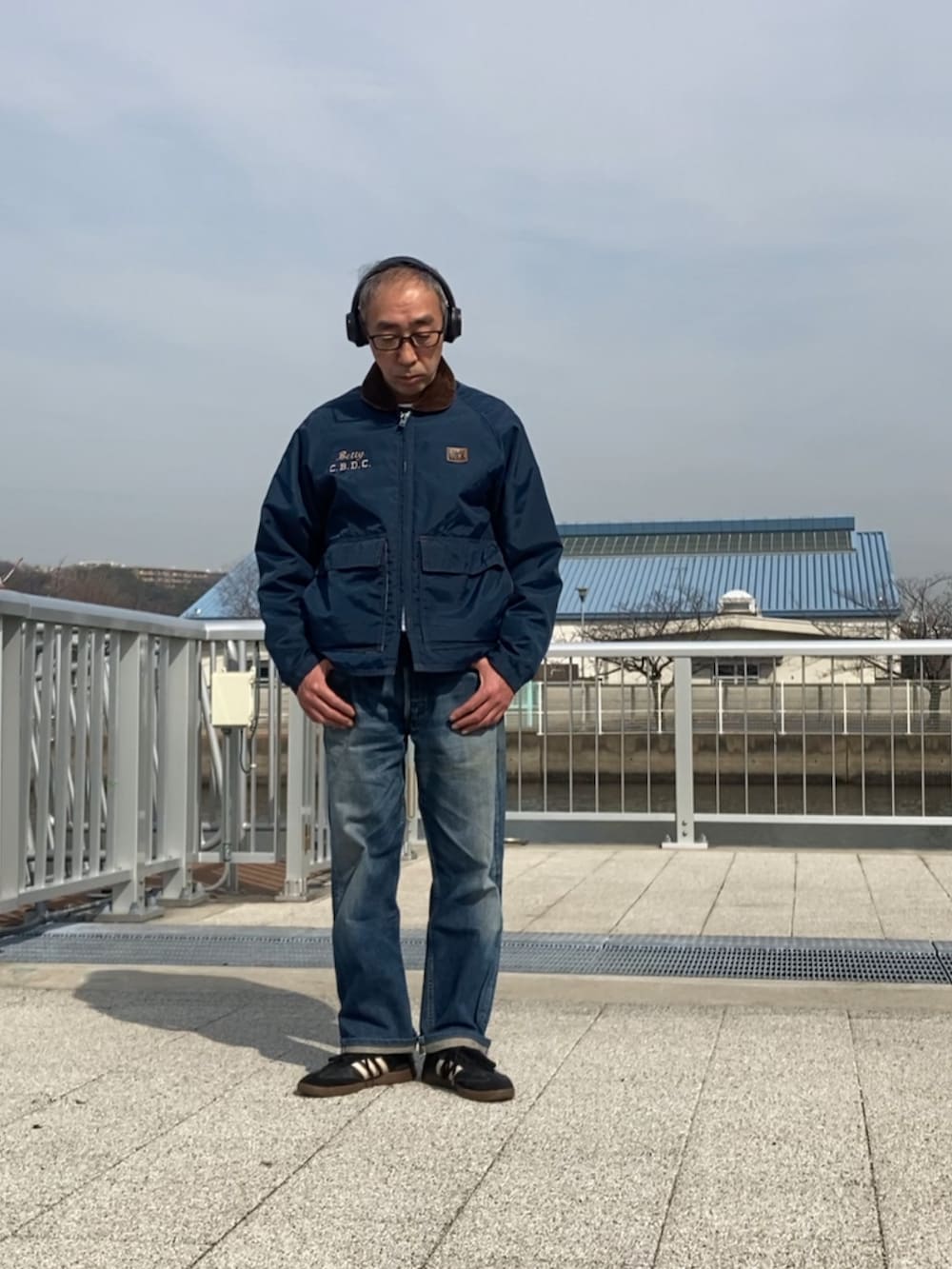 ブルー系のナイロンジャケット、ブルー系のデニムパンツ、ブラック系のスニーカーを着用したメンズの冬コーディネートの2枚目の写真