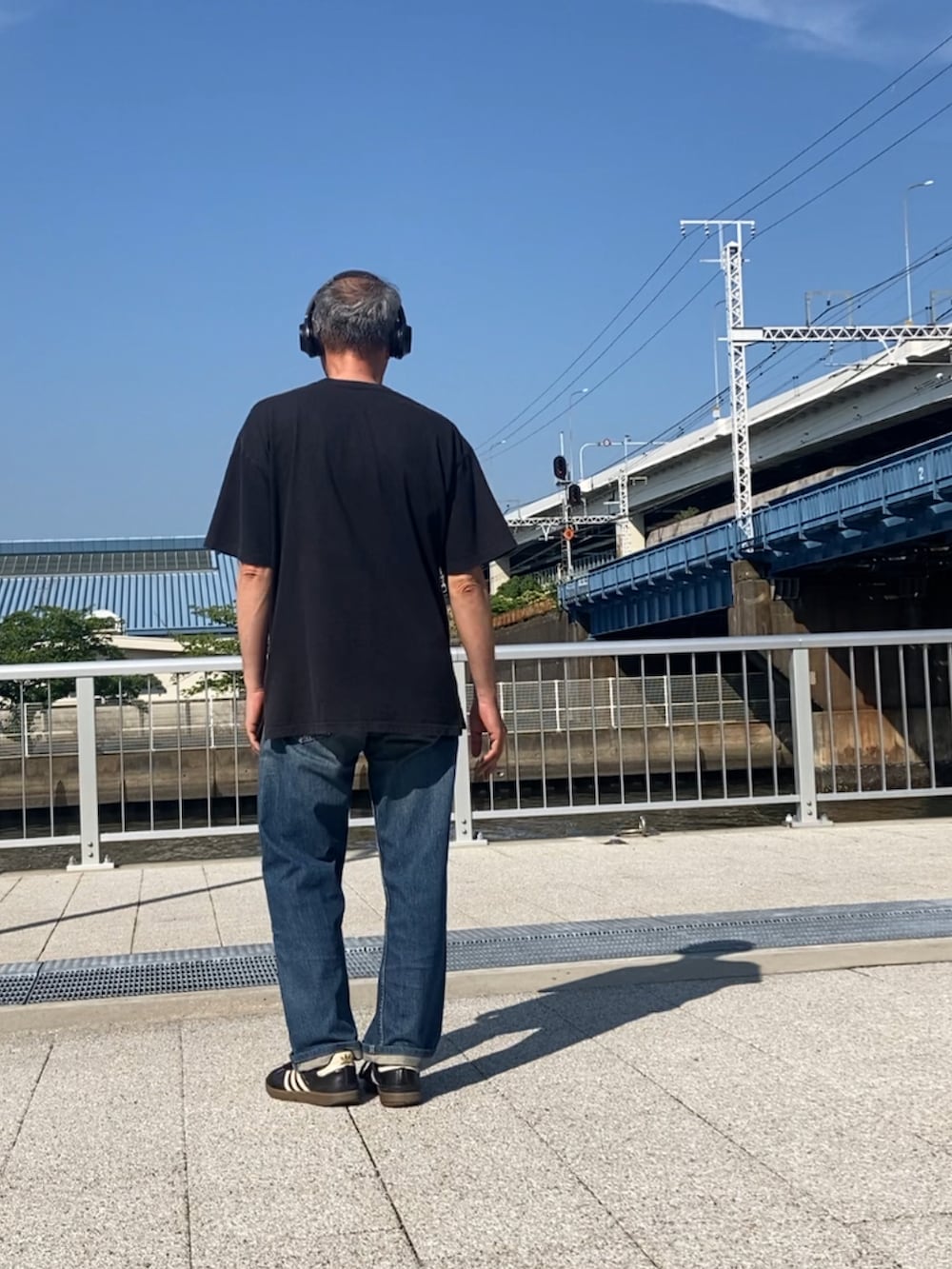 ブルー系のデニムパンツ、ブラック系のTシャツ/カットソー、ブラック系のスニーカーを着用したメンズの夏コーディネートの3枚目の写真