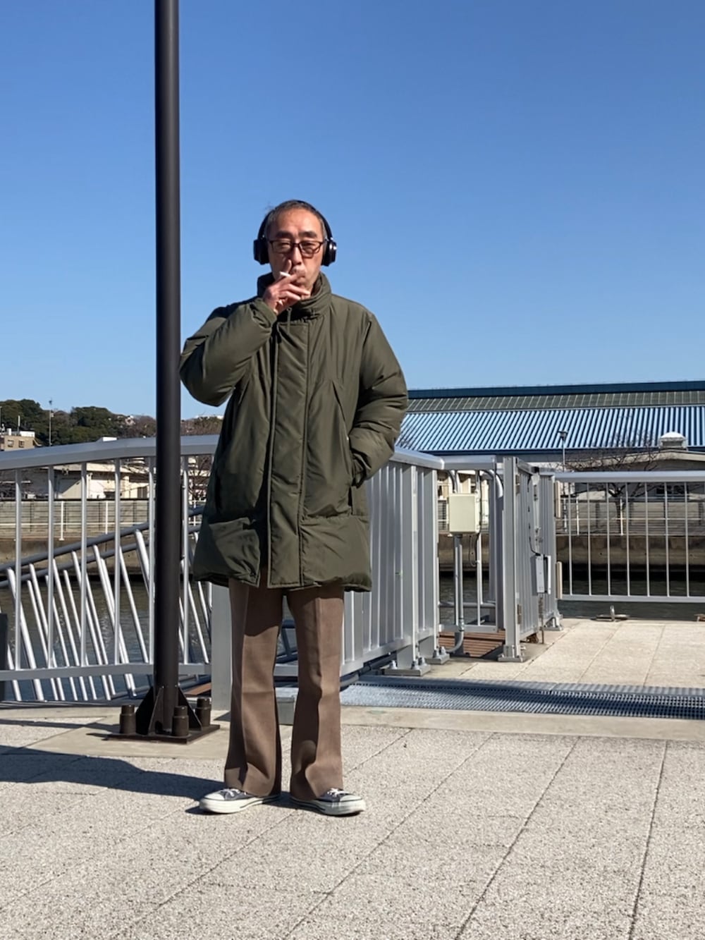 グリーン系のダウンジャケット/コート、ブラウン系のスラックス、ブルー系のスニーカーを着用したメンズの冬コーディネートの3枚目の写真