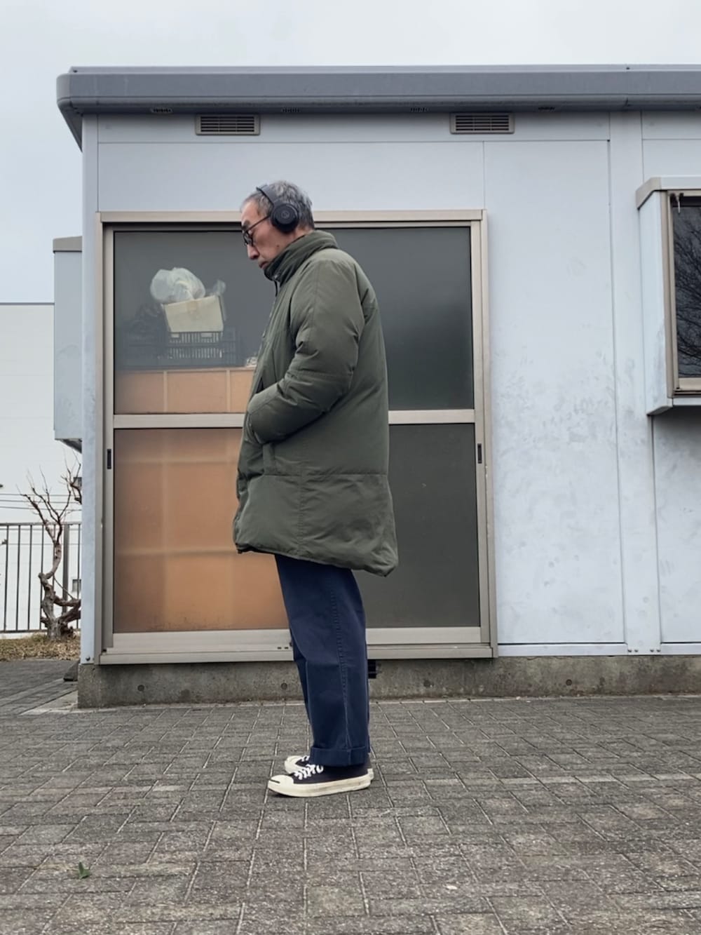 グリーン系のダウンジャケット/コート、ブルー系のチノパンツ、ブラック系のスニーカーを着用したメンズの冬コーディネートの2枚目の写真