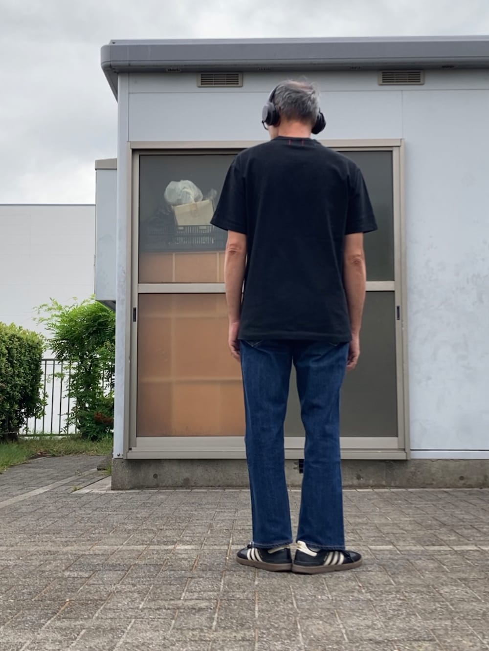 ブルー系のデニムパンツ、ブラック系のTシャツ/カットソー、ブラック系のスニーカーを着用したメンズの秋コーディネートの2枚目の写真