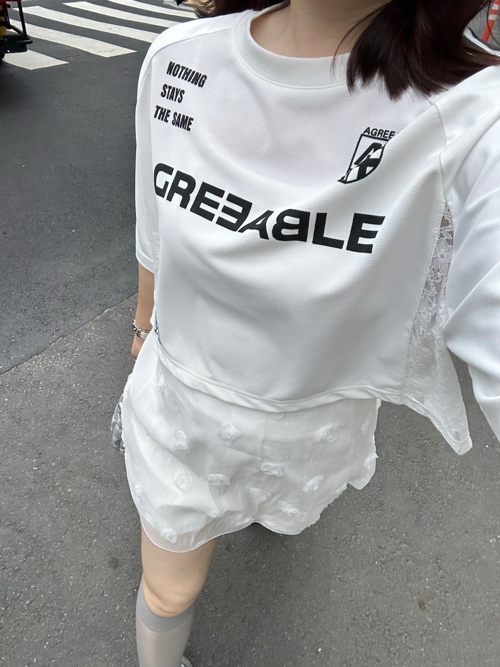 ホワイト系のTシャツ/カットソー、シルバー系のショルダーバッグ、ホワイト系のスカートを着用したレディースの夏コーディネートの3枚目の写真