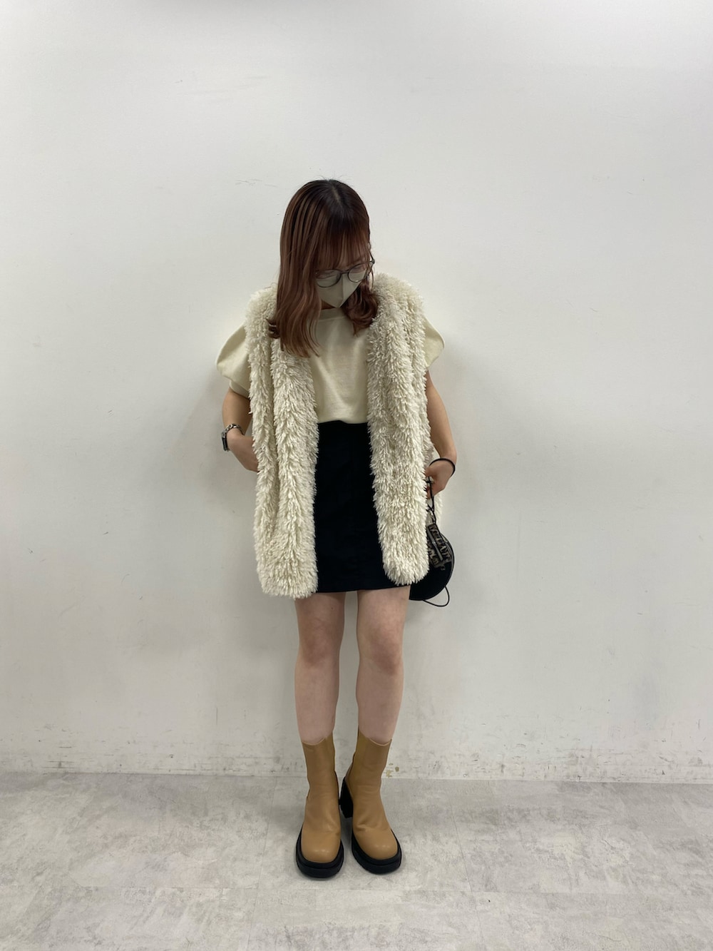 ホワイト系のニット/セーター、ブラック系のスカート、ホワイト系のダウンベストを着用したレディースの夏コーディネートの2枚目の写真