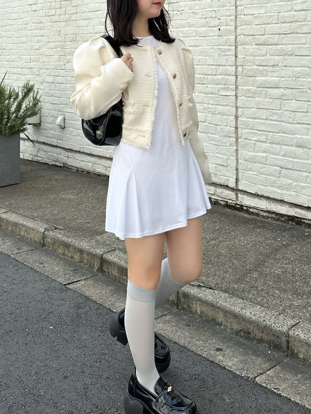 ホワイト系のノーカラージャケット、ホワイト系のチュニック、ブラック系のローファーを着用したレディースの秋コーディネートの2枚目の写真