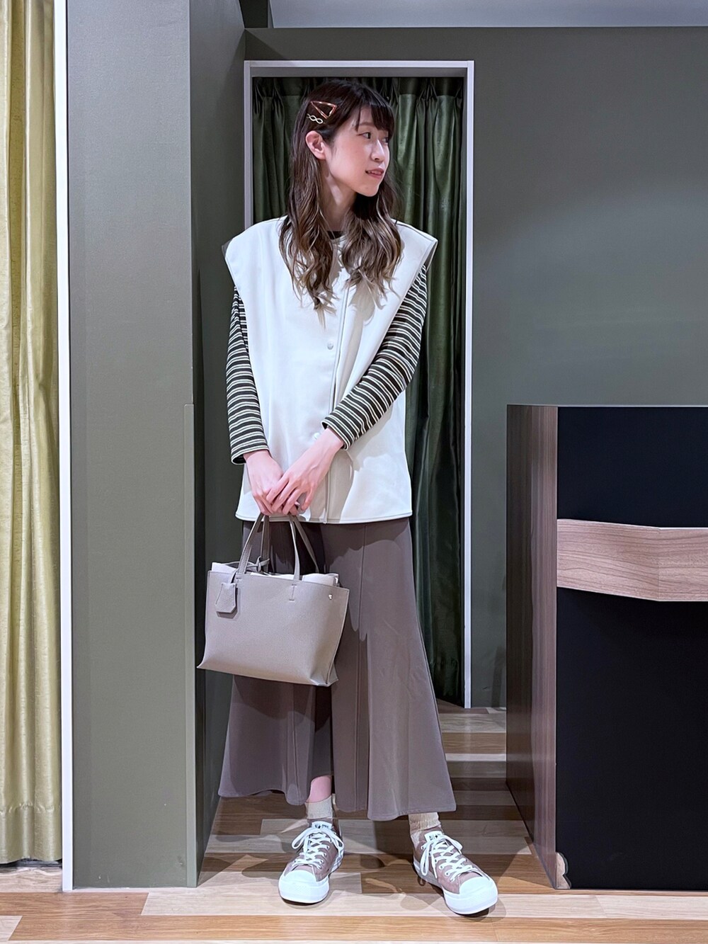 ベージュ系のベスト、グレー系のTシャツ/カットソー、ブラウン系のスカートを着用したレディースの秋コーディネートの2枚目の写真