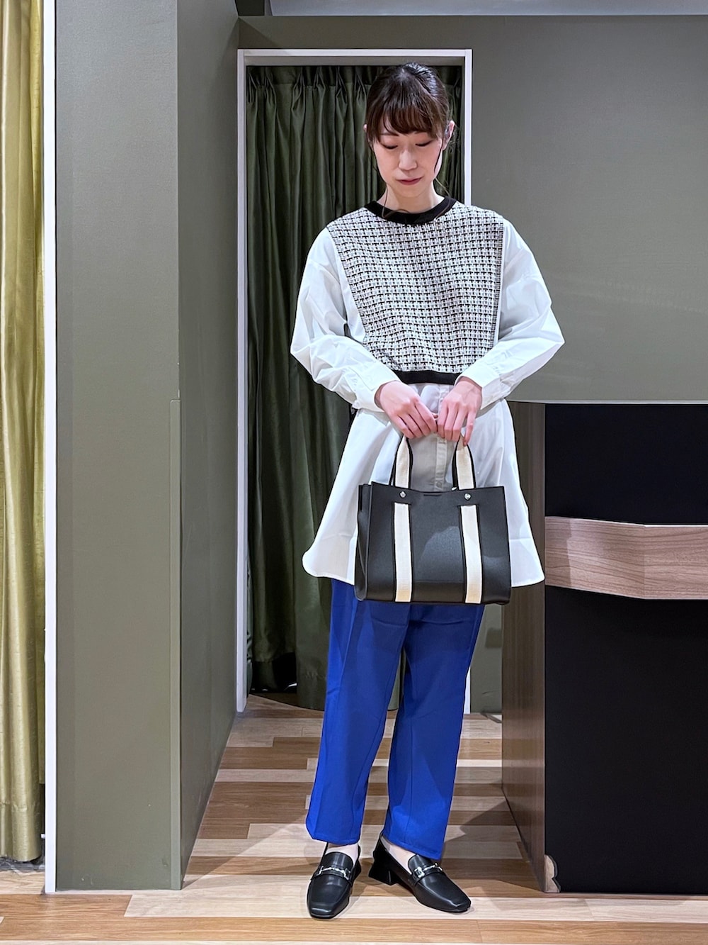 ホワイト系のチュニック、ブルー系のその他パンツ、ブラック系のハンドバッグを着用したレディースの春コーディネートの3枚目の写真