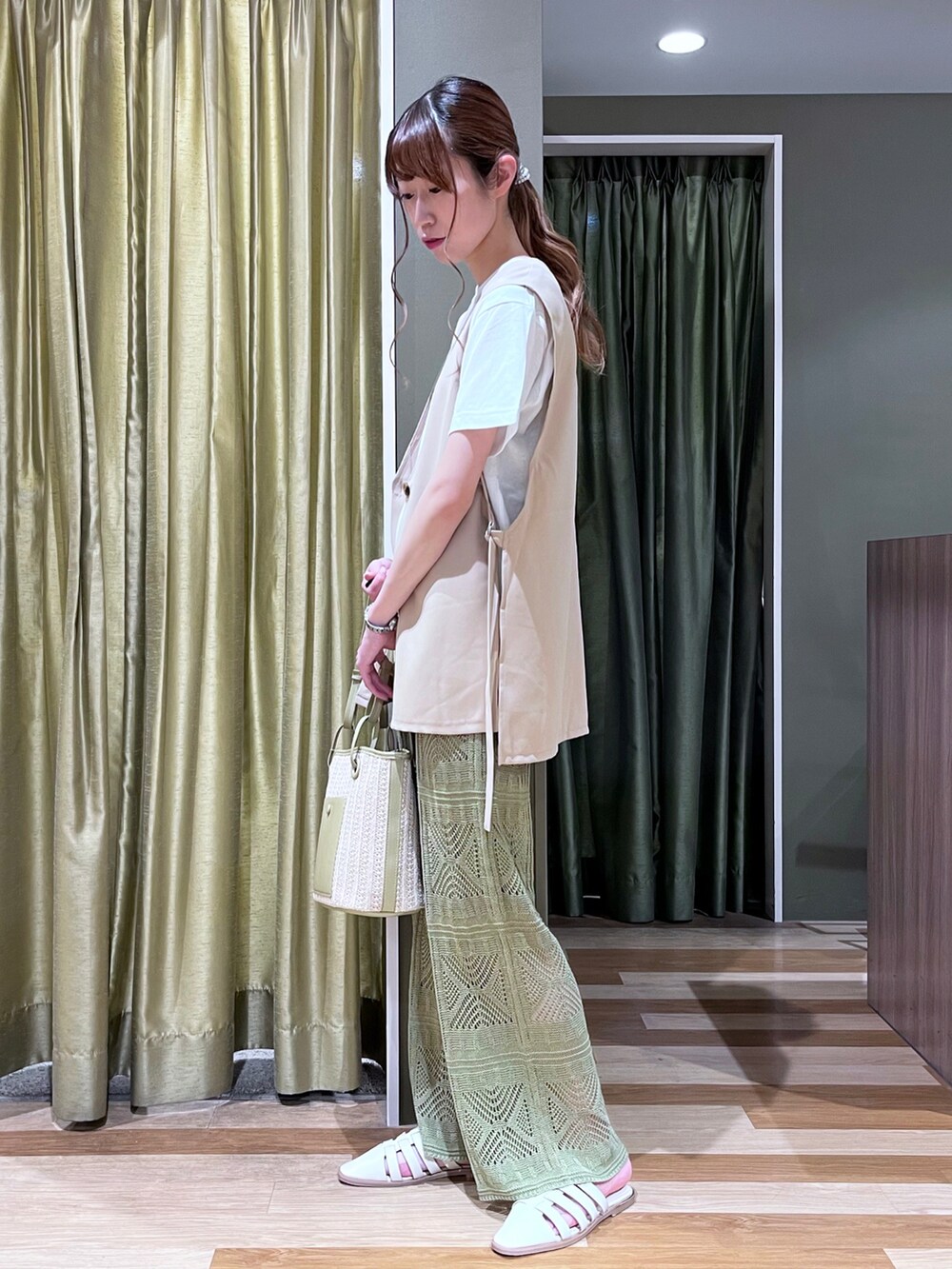 ベージュ系のベスト、ホワイト系のTシャツ/カットソー、ホワイト系のサンダルを着用したレディースの春コーディネートの2枚目の写真