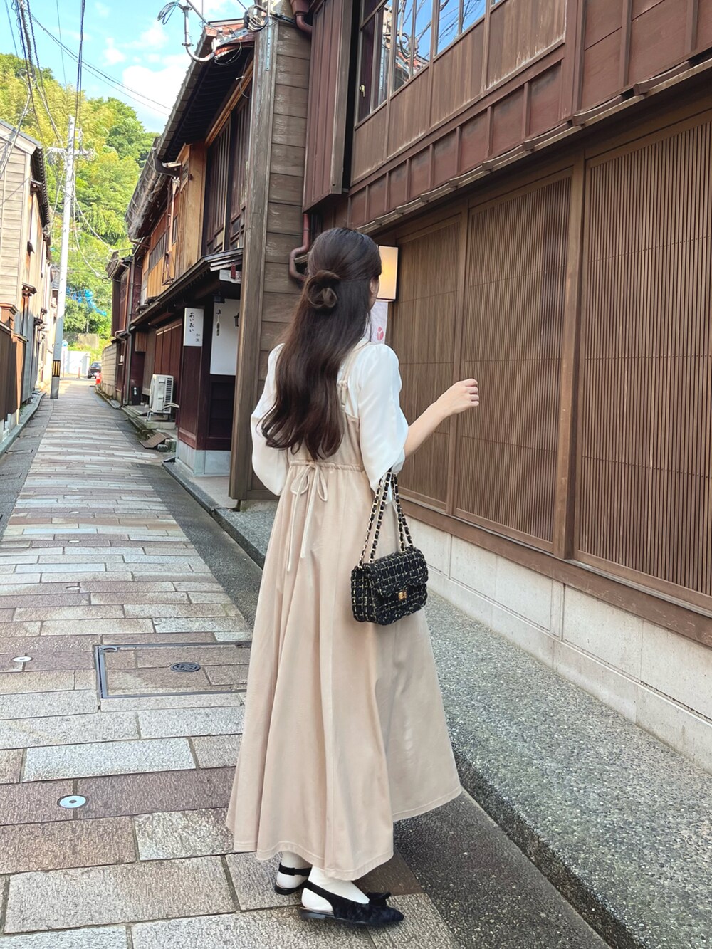 ホワイト系のワンピース、ブラック系のパンプス、ブラック系のショルダーバッグを着用したレディースの秋コーディネートの3枚目の写真