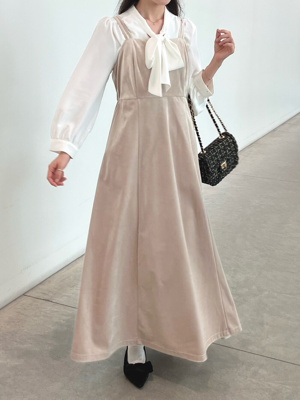 ホワイト系のワンピース、ブラック系のパンプス、ブラック系のショルダーバッグを着用したレディースの秋コーディネートの2枚目の写真