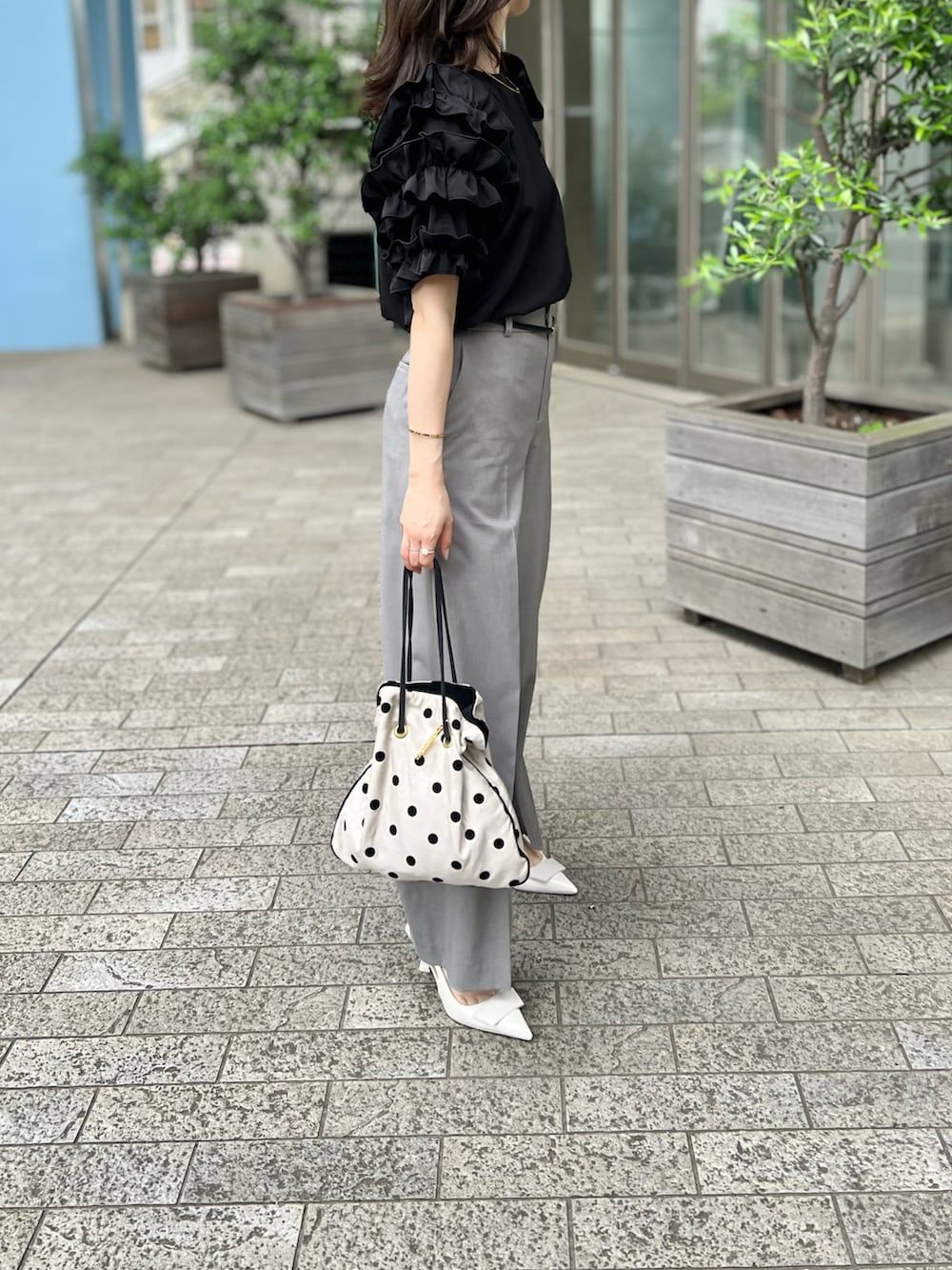 ブラック系のTシャツ/カットソー、グレー系のパンツ、ホワイト系のパンプスを着用したレディースの春コーディネートの3枚目の写真