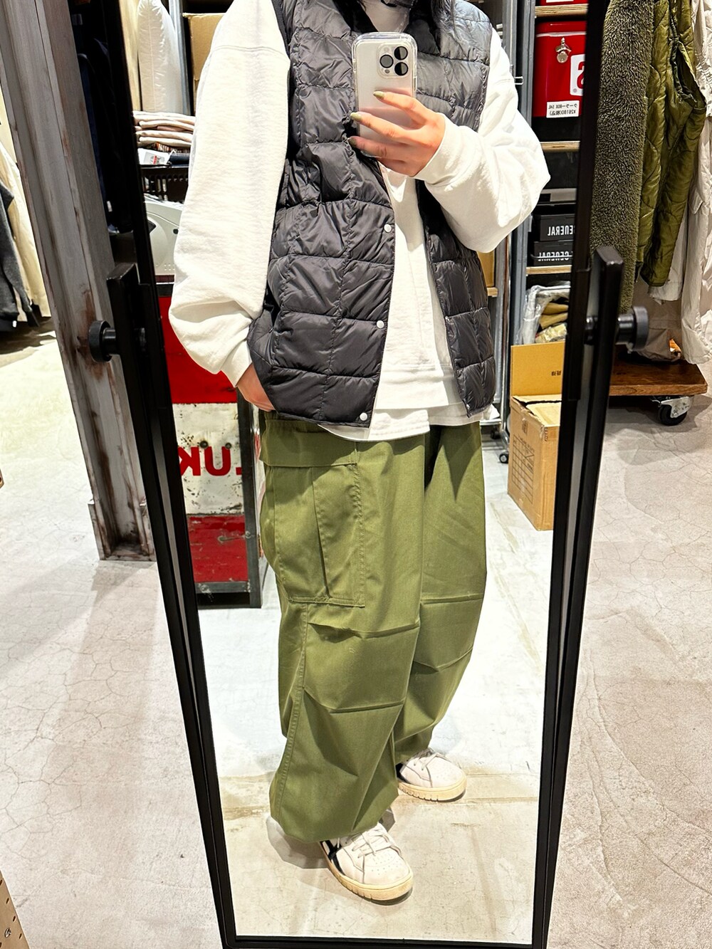 ホワイト系のスニーカー、グリーン系のカーゴパンツ、ブラック系のダウンベストを着用したレディースの冬コーディネートの2枚目の写真