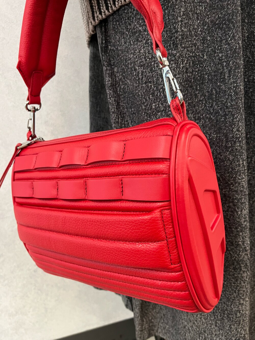 レッド系のショルダーバッグ、ブラック系のブーツ、ブラック系のスカートを着用したレディースの秋コーディネートの2枚目の写真