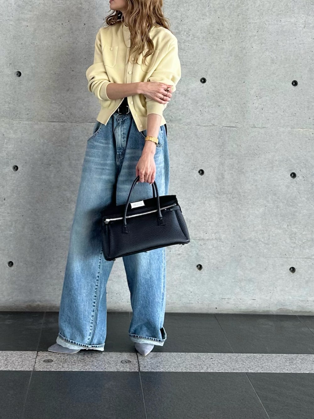 ブルー系のデニムパンツ、ブラック系のハンドバッグ、イエロー系のカーディガン/ボレロを着用したレディースの春コーディネートの4枚目の写真
