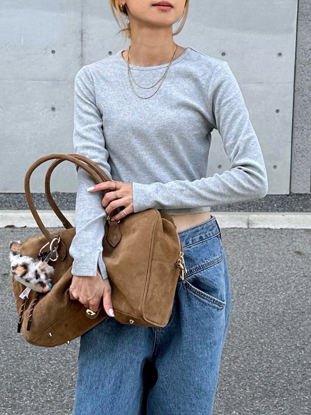 ブラウン系のボストンバッグ、ブルー系のデニムパンツ、ブラウン系のスニーカーを着用したレディースの夏コーディネートの3枚目の写真