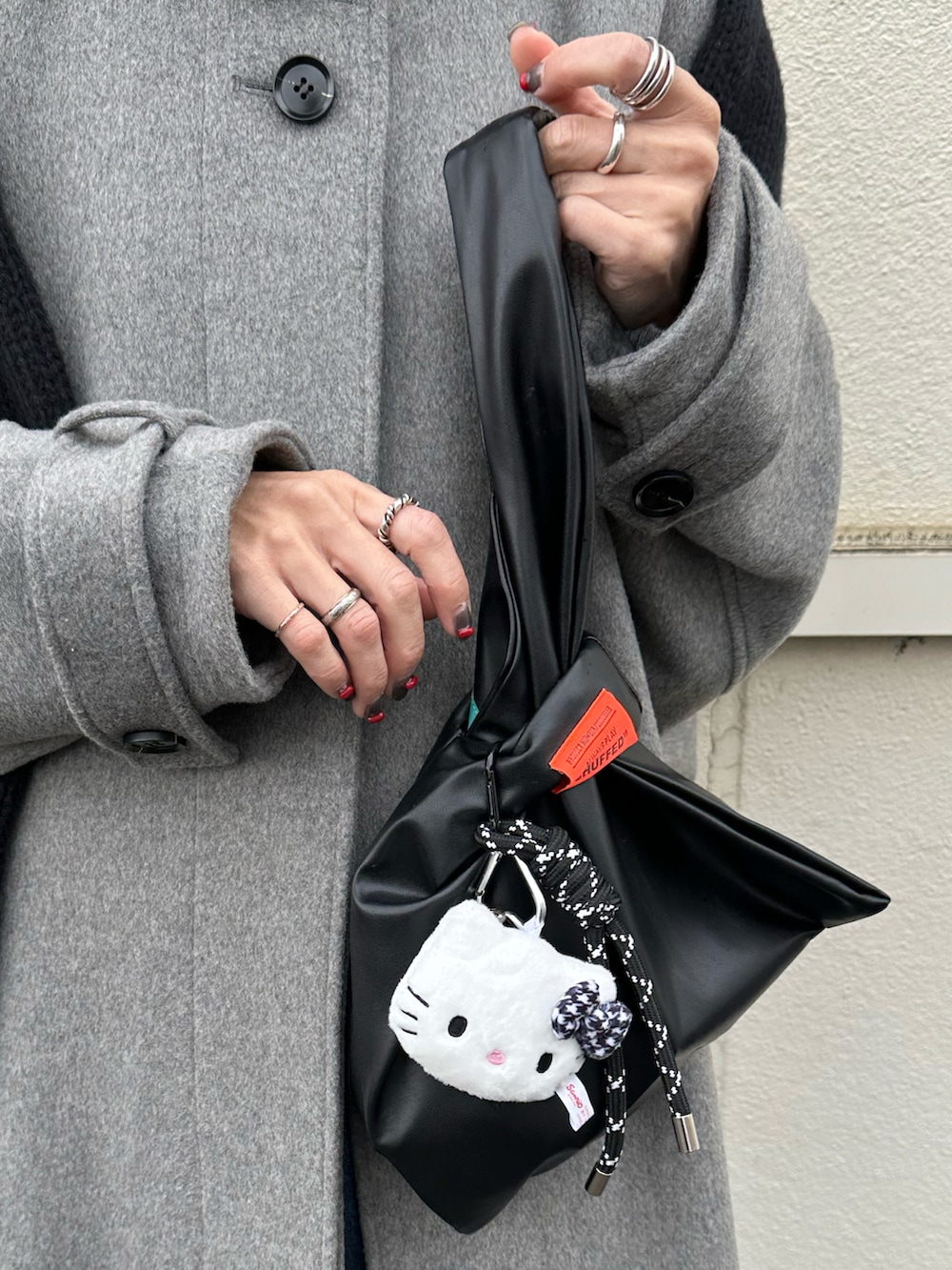 グレー系のステンカラーコート、ブラック系のハンドバッグ、ブルー系のキャップを着用したレディースの冬コーディネートの3枚目の写真