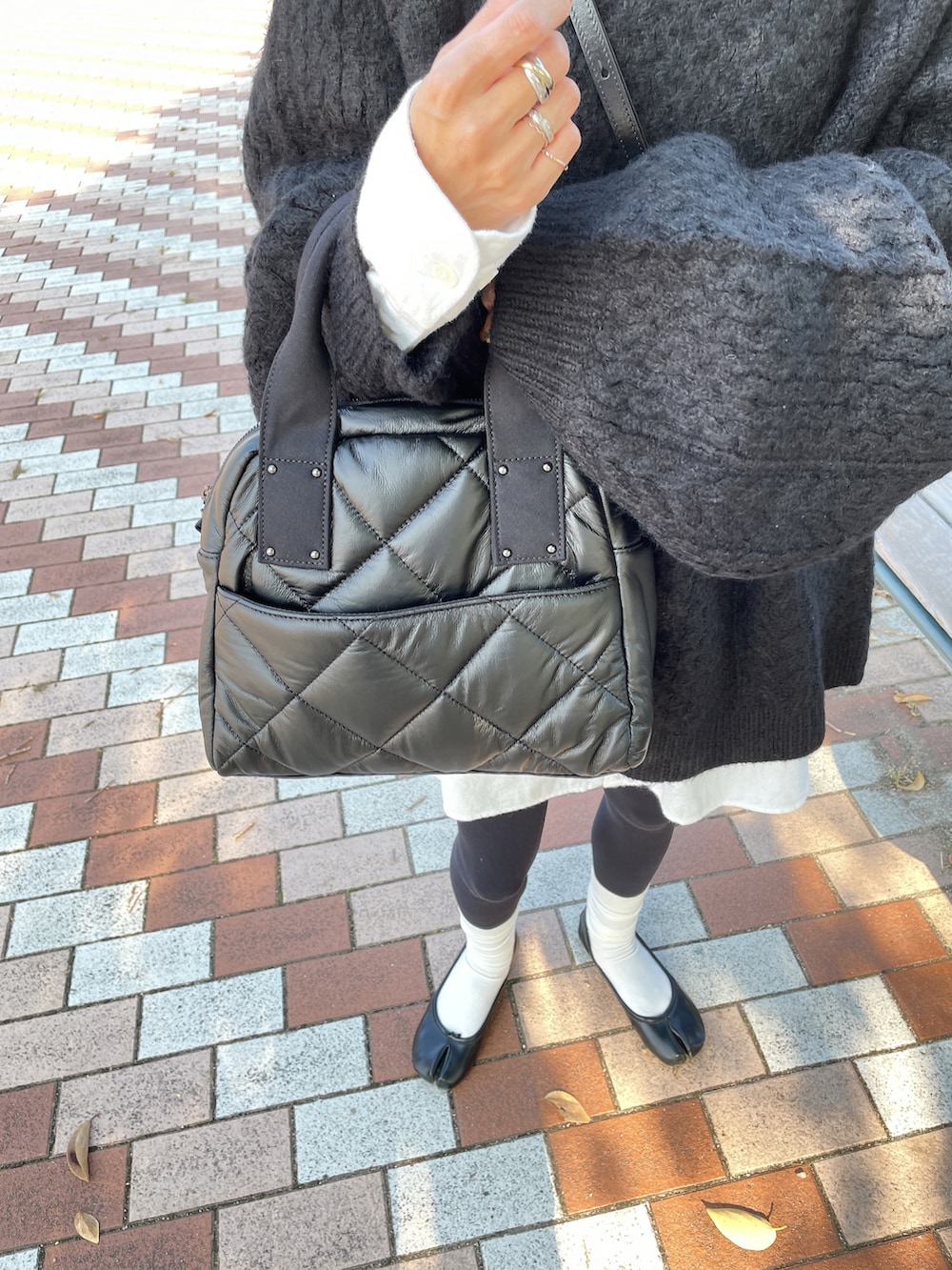 グリーン系のニット/セーター、ブラック系のトートバッグを着用したレディースの秋コーディネートの2枚目の写真