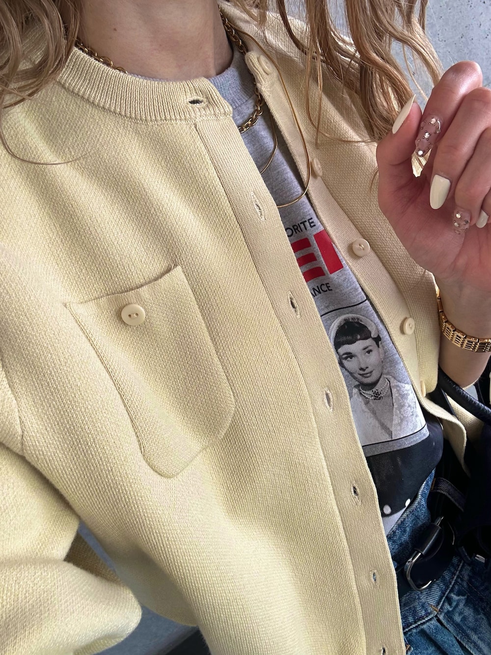 ブルー系のデニムパンツ、ブラック系のハンドバッグ、イエロー系のカーディガン/ボレロを着用したレディースの春コーディネートの5枚目の写真