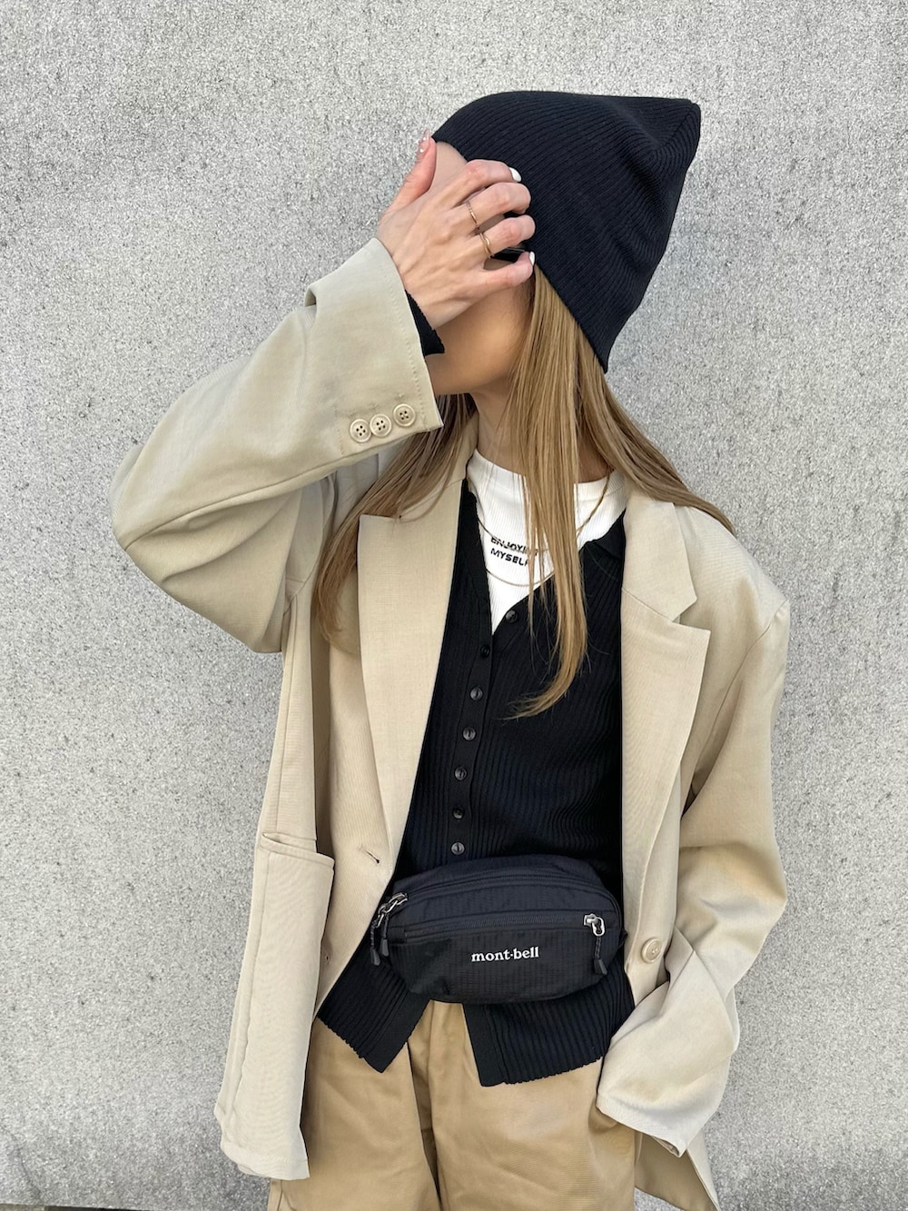 ブラック系のボディバッグ/ウエストポーチ、ベージュ系のテーラードジャケット、ブラック系のカーディガン/ボレロを着用したレディースの春コーディネートの2枚目の写真