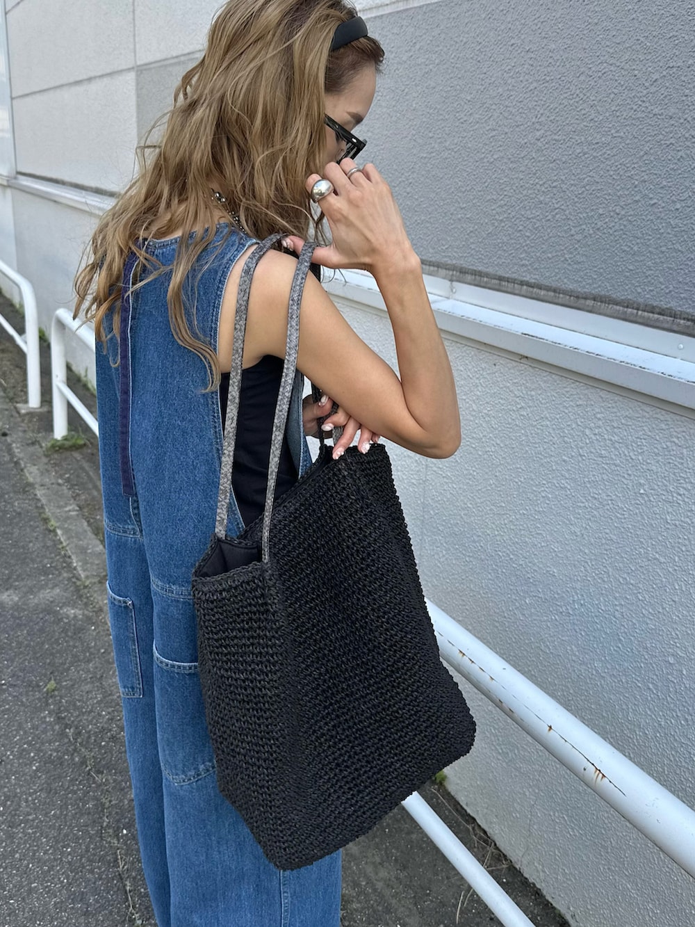 ブルー系のサロペット/オーバーオール、ブラック系のかごバッグを着用したレディースの夏コーディネートの4枚目の写真