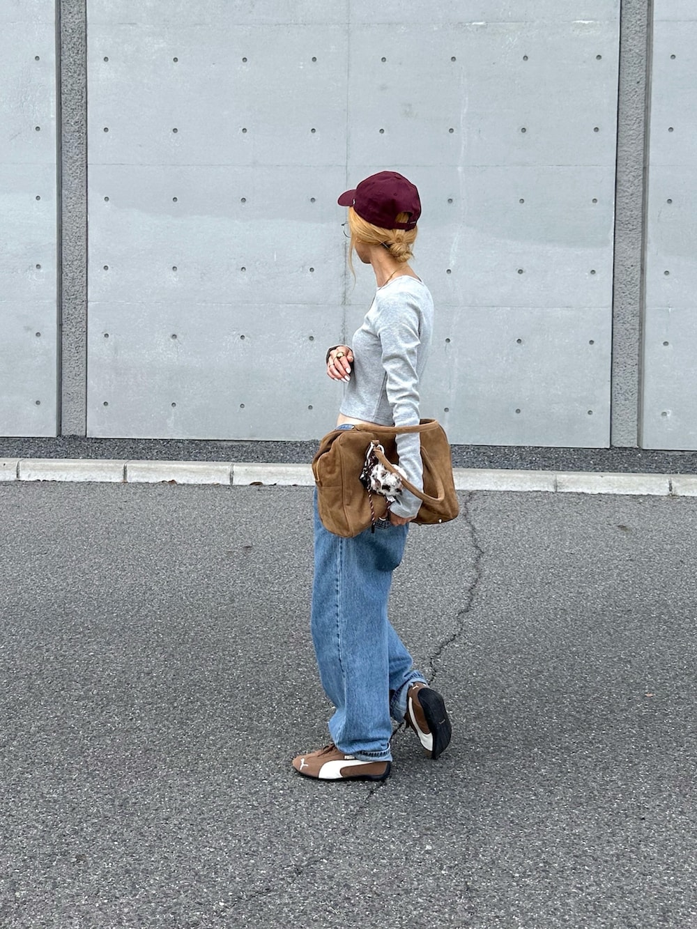 ブラウン系のボストンバッグ、ブルー系のデニムパンツ、ブラウン系のスニーカーを着用したレディースの夏コーディネートの2枚目の写真