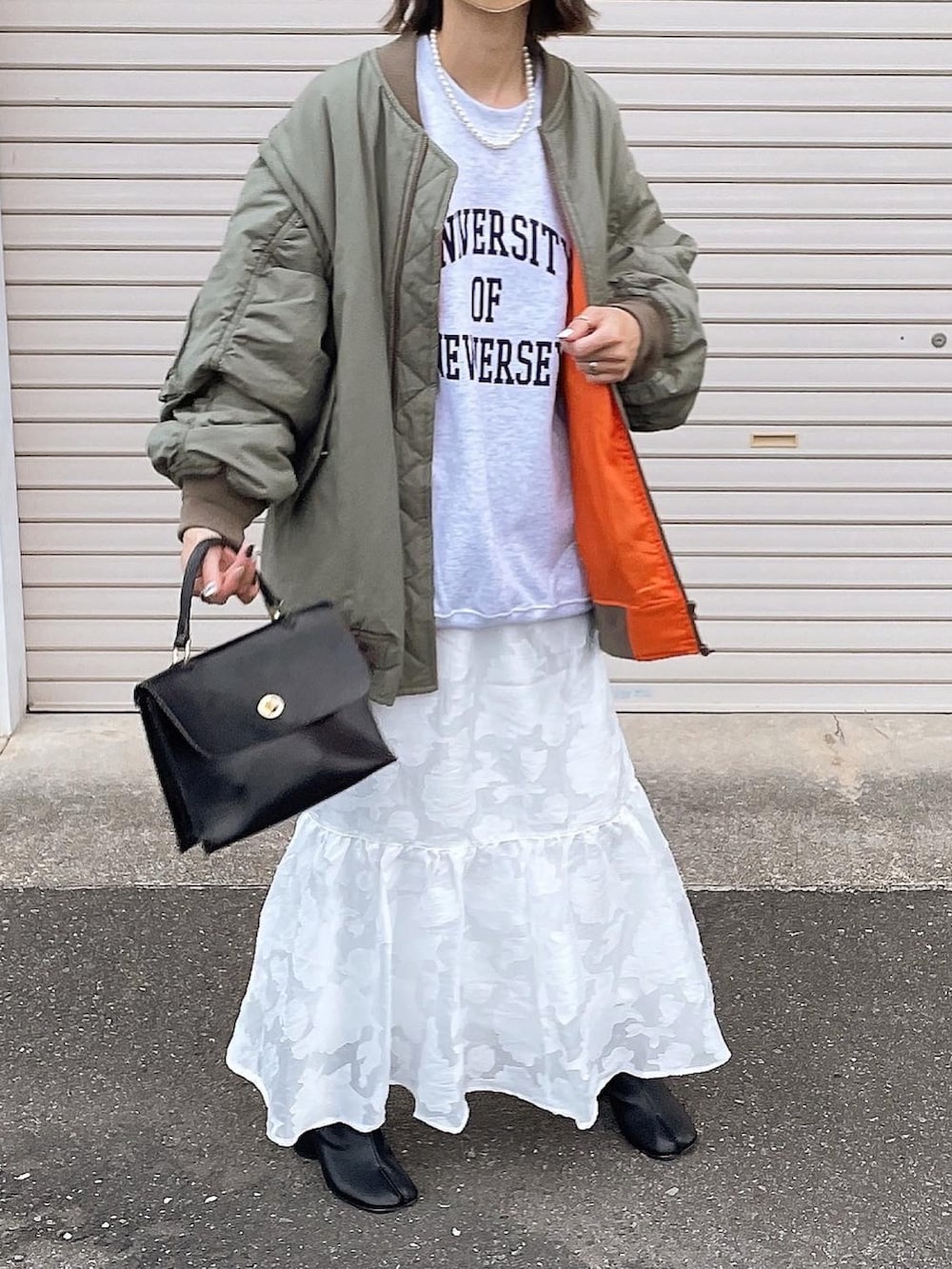 グリーン系のMA-1、ホワイト系のスカートを着用したレディースの秋コーディネートの3枚目の写真