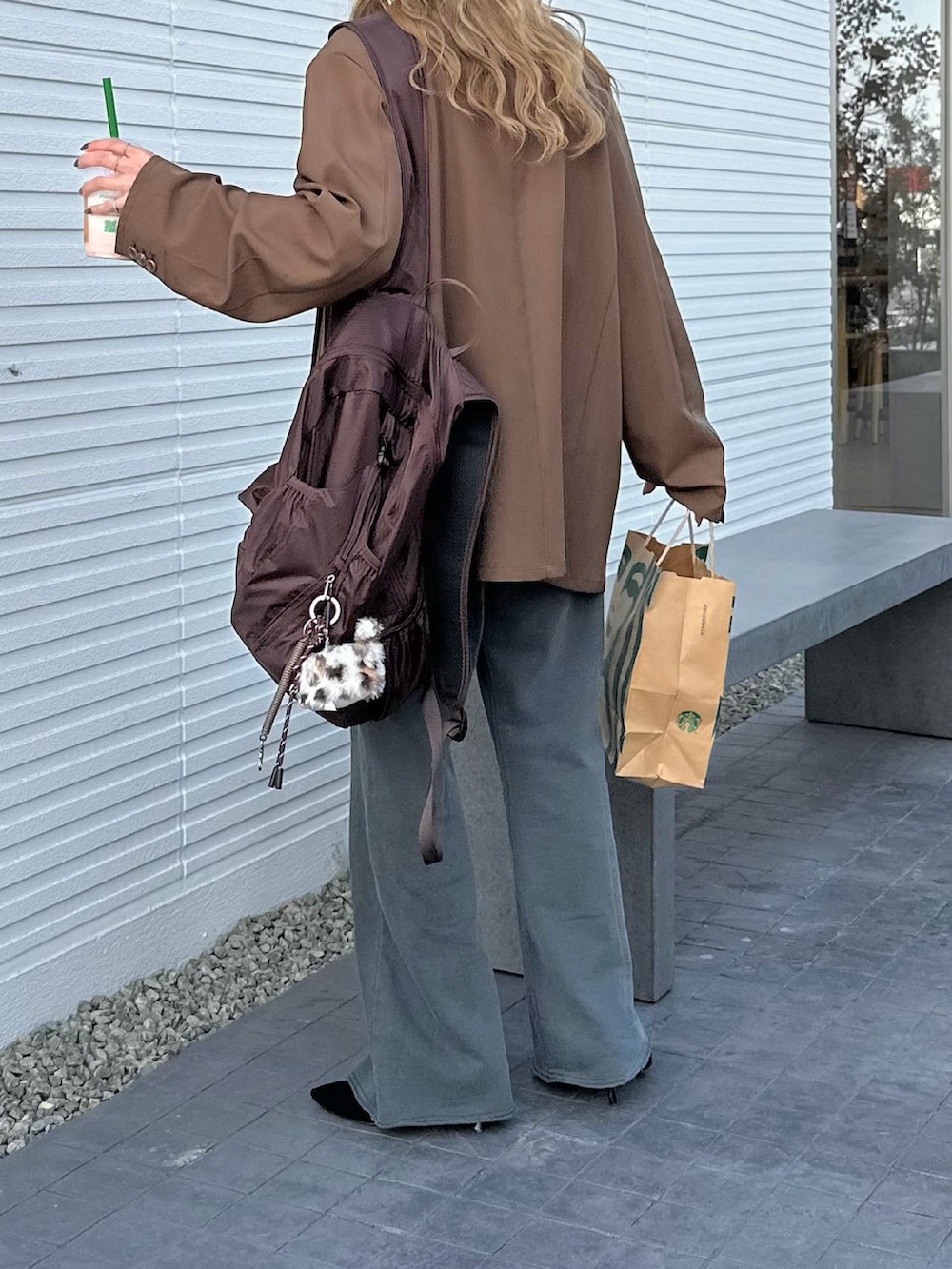 ブラウン系のテーラードジャケット、ブラウン系のバックパック/リュック、グレー系のスウェットパンツを着用したレディースの春コーディネートの3枚目の写真