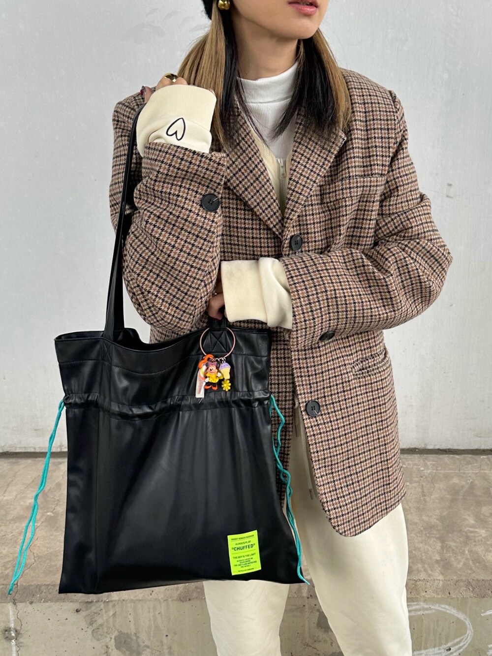 ブラウン系のテーラードジャケット、ブラック系のトートバッグ、ホワイト系のつなぎ/オールインワンを着用したレディースの冬コーディネートの3枚目の写真