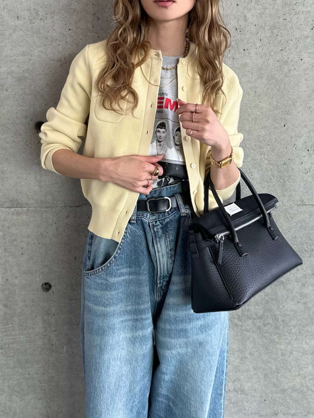 ブルー系のデニムパンツ、ブラック系のハンドバッグ、イエロー系のカーディガン/ボレロを着用したレディースの春コーディネートの3枚目の写真