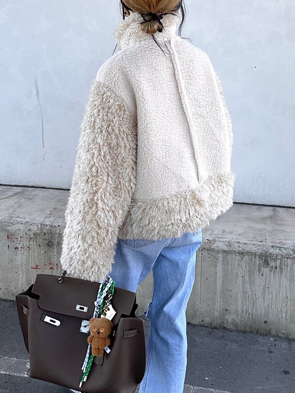 ホワイト系のムートンコートを着用したレディースの秋コーディネートの4枚目の写真