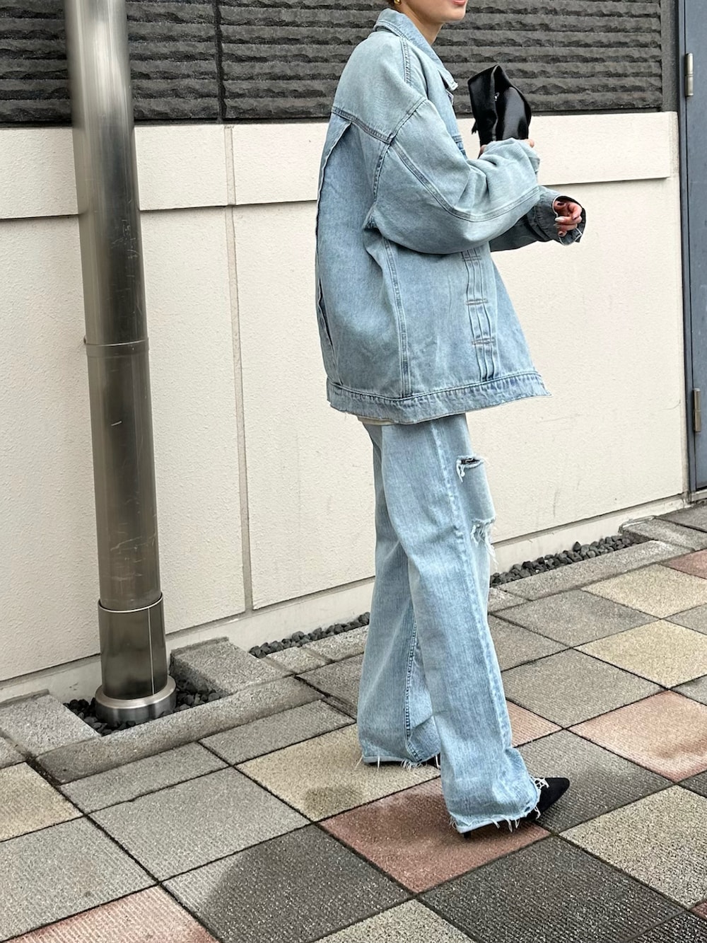 ブルー系のデニムジャケット、ブラック系のパンプスを着用したレディースの春コーディネートの4枚目の写真